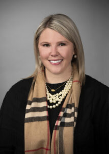 Photo of a woman in a black shirt and multi-colored scarf, smiling.